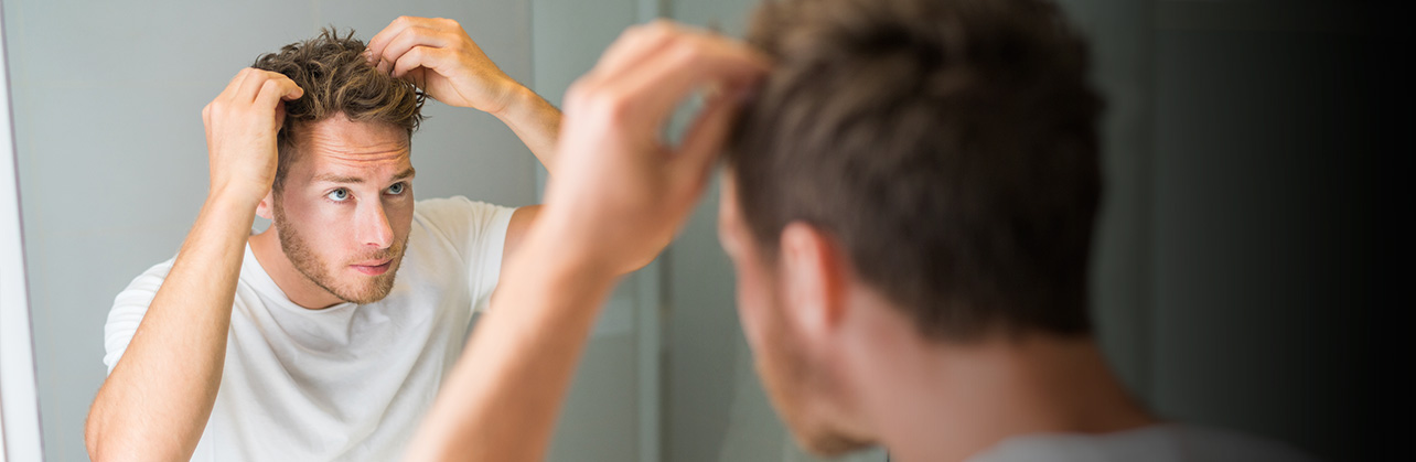 Total Hair Restoration man checking hair in mirror