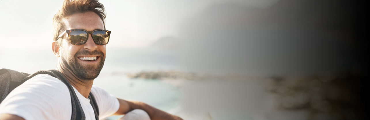 man sitting on cliff looking at camera