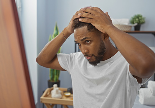 Total Hair Restoration man checking out hairline in mirror